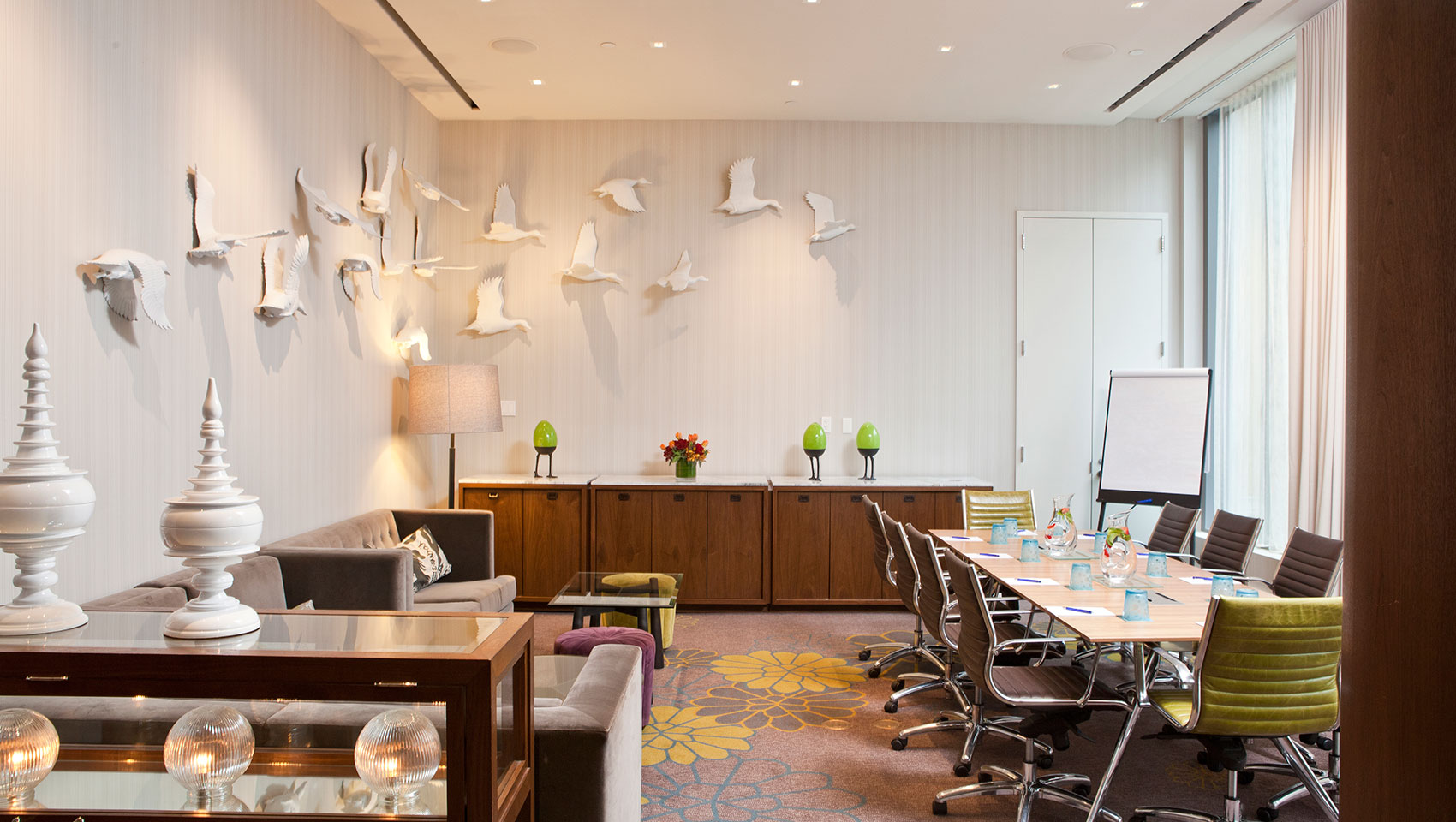 Invent I meeting space with meeting table set with glasses and notepads in sunlit room with flying duck art pieces