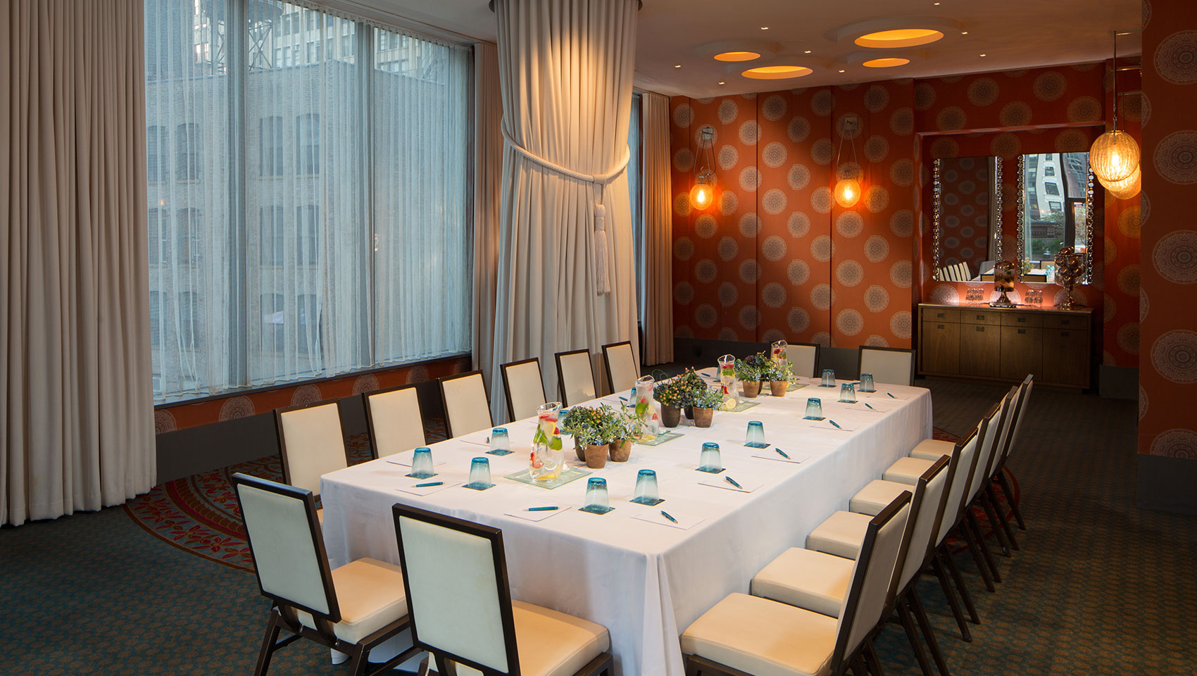 Verdi I boardroom meeting with drawn curtains and meeting table with notepads, floral pieces, and glasses on table