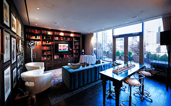 Kimpton Hotel Eventi's Eventi Suite living area with high top table, book-filled shelves in room with large windows and balcony