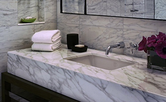 Marble countertop sink with stacked towels and flowers