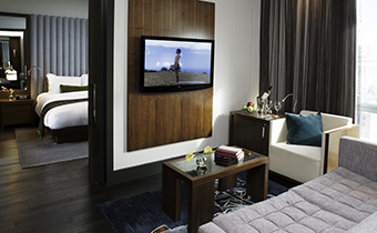 Kimpton Hotel Eventi Executive one bedroom suite living area with seating, coffee table, and mounted television