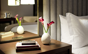Guest room bedside nightstand with flowers in a vase next to stacked books