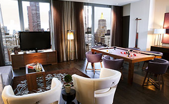 Kimpton Hotel Eventi suite living area with pool table and surrounding seating and views of city buildings