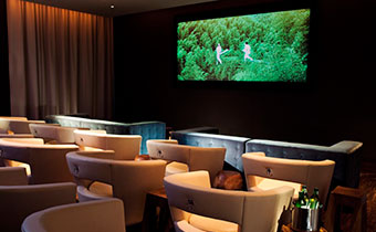 Kimpton Hotel Eventi screening room with oversized seating facing a large screen in a dark room