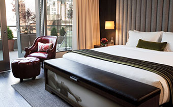 Kimpton Hotel Eventi guest room bed next to leather seating and ottoman