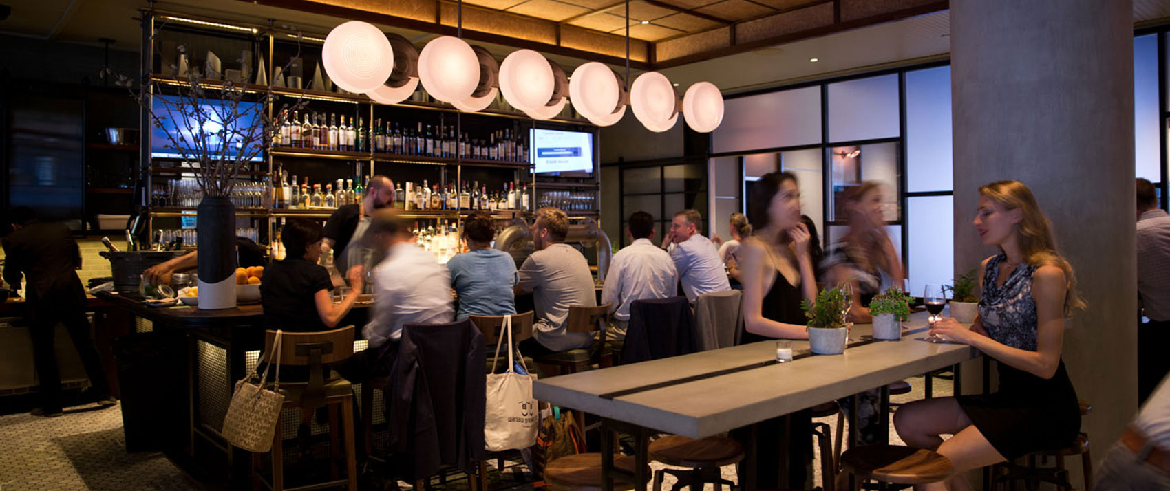 The Vine seating with guests enjoying drinks at the bar and communal table